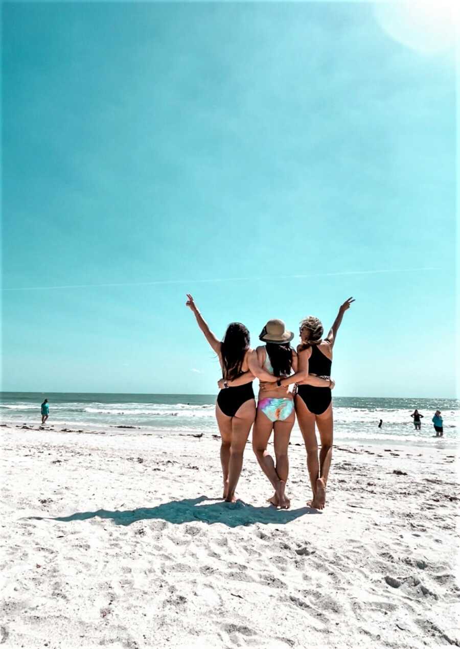 woman and her friends posing on the beach looking at the ocean