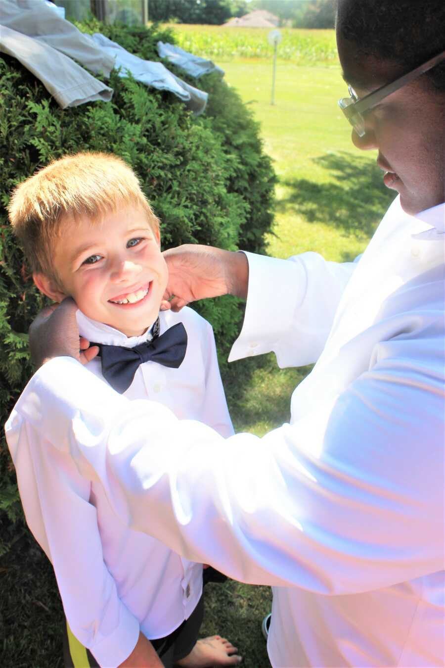 Stepmom fixes her oldest son's bowtie during wedding photos