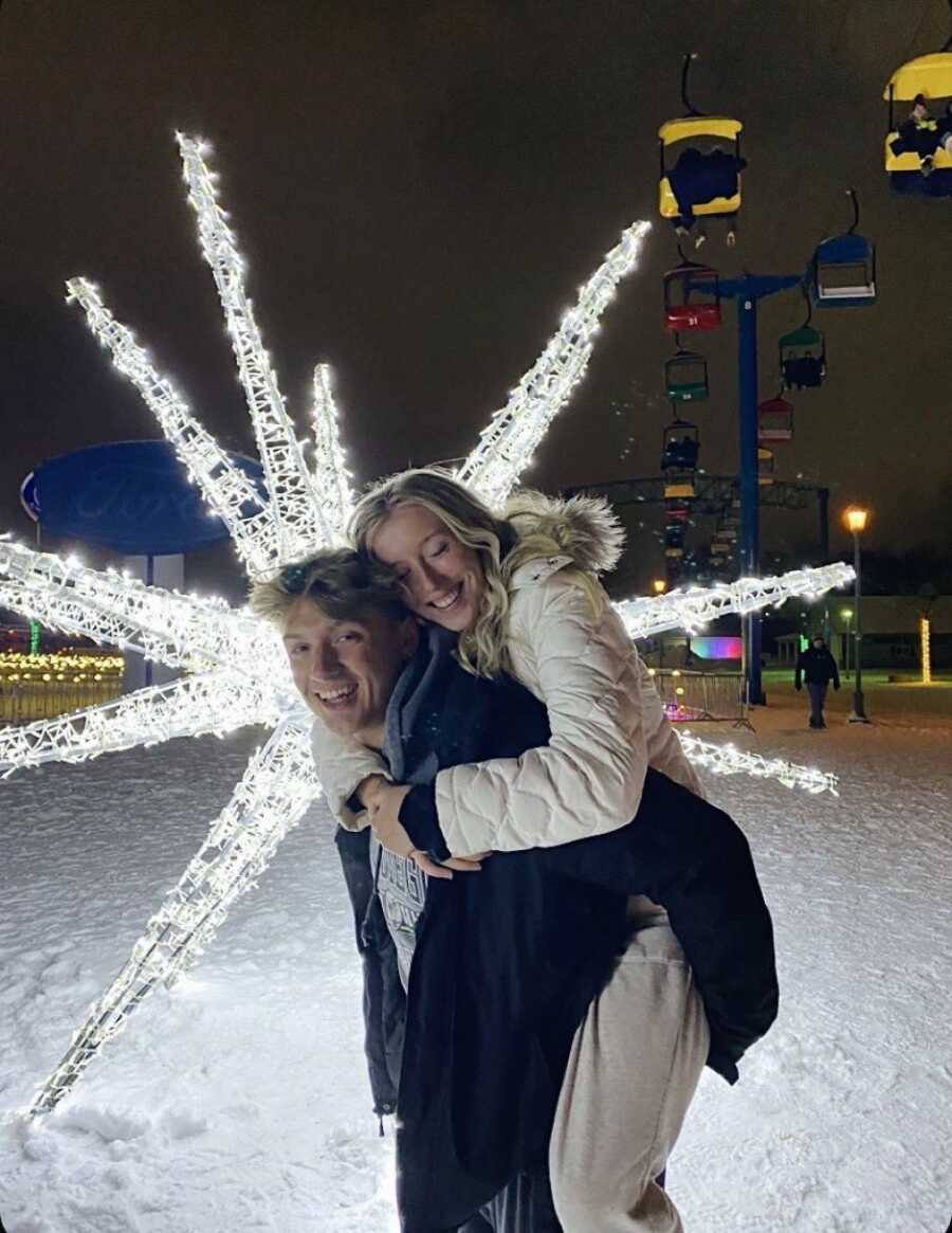 couple taking a photo in front of christmas lights