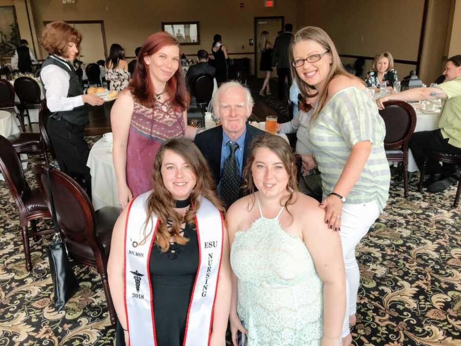 Sisters take family photo with their father on the day of one of the sister's nursing school graduation