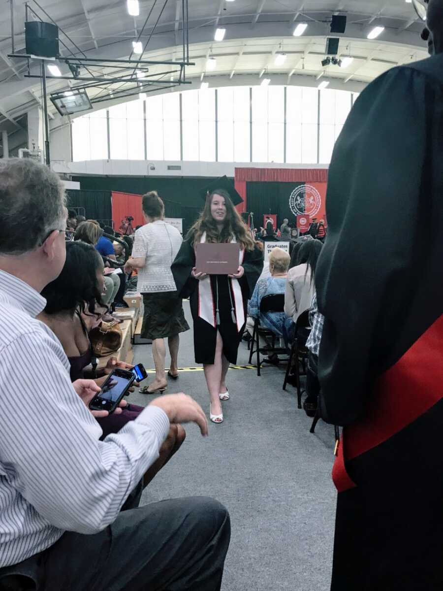 Girl walks towards her family after receiving her diploma at graduation