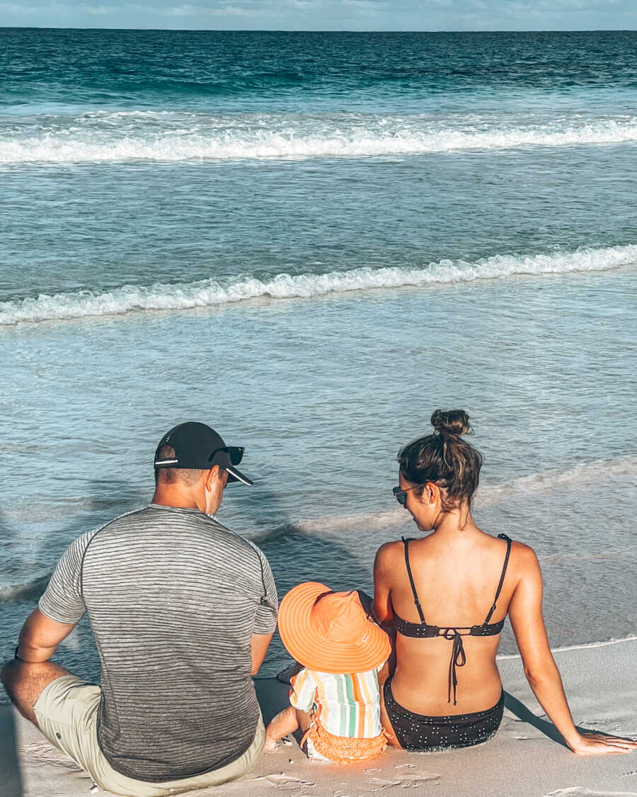 mom and dad on a beach with their daughter