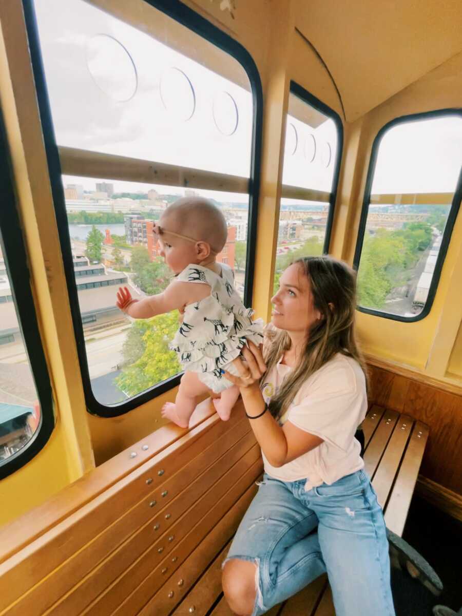 mom holding her daughter up on a bus