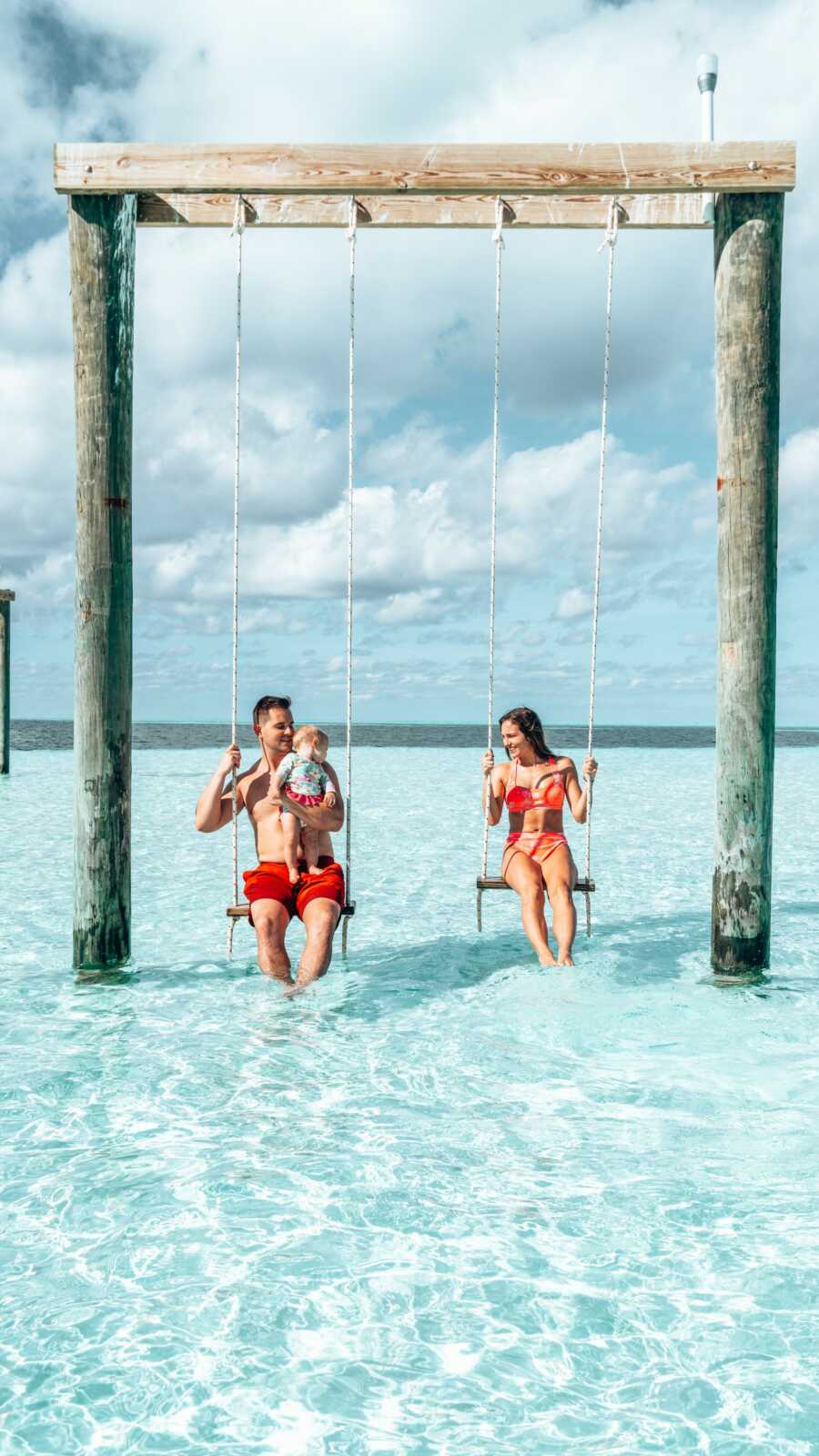 mom dad and daughter on a beach swing