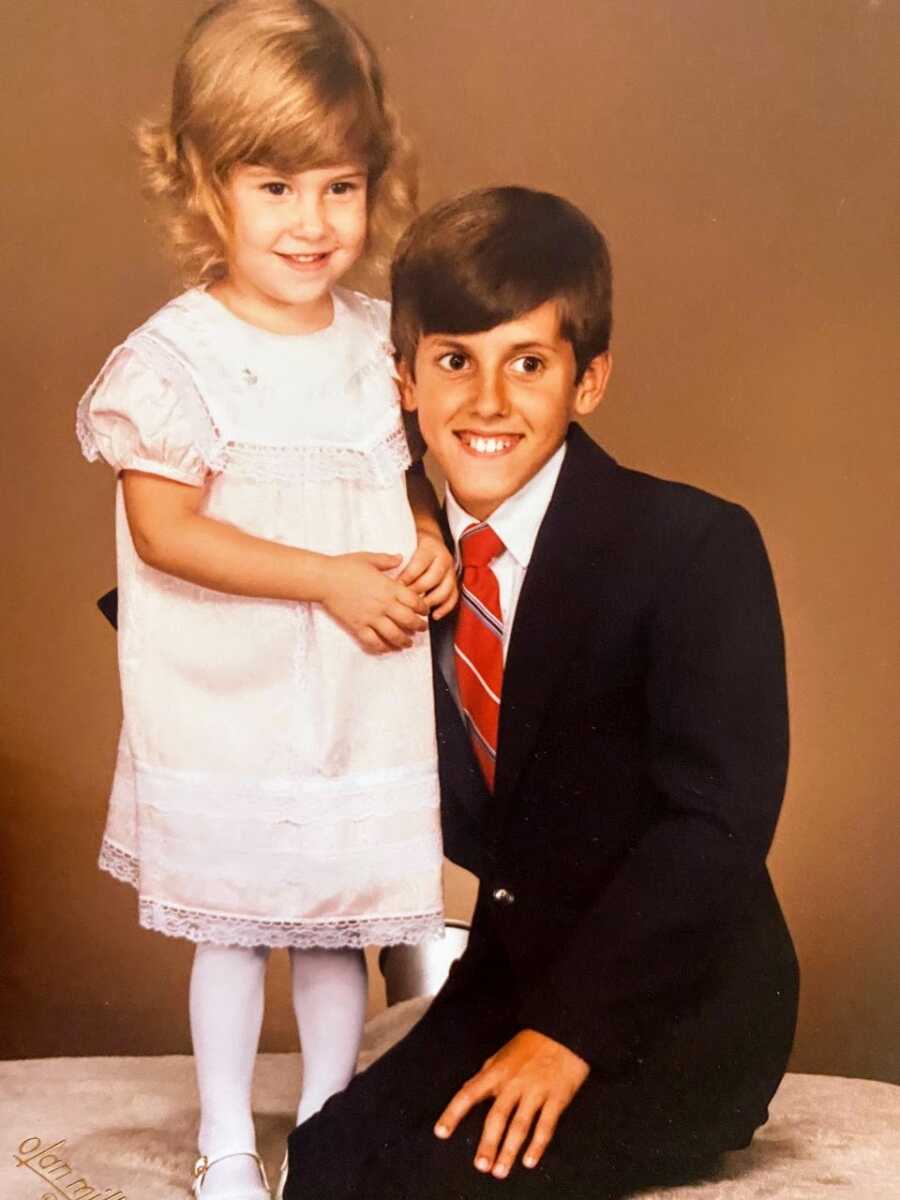 Brother and sister smile while taking formal family photos in a studio