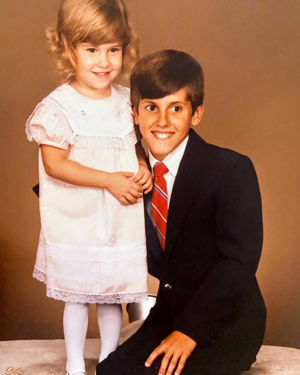 Brother and sister smile while taking formal family photos in a studio