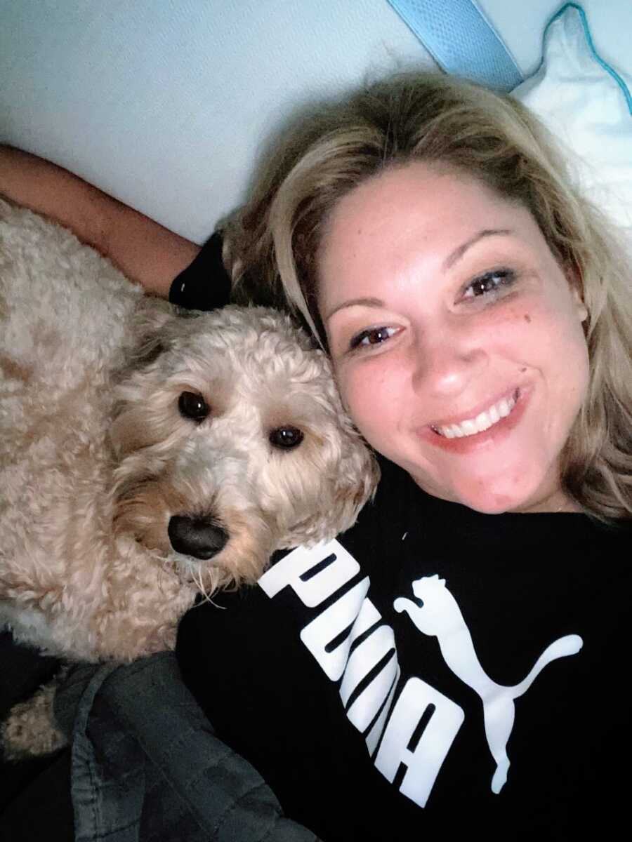 Adoptee takes a selfie with her dog while they cuddle in bed together