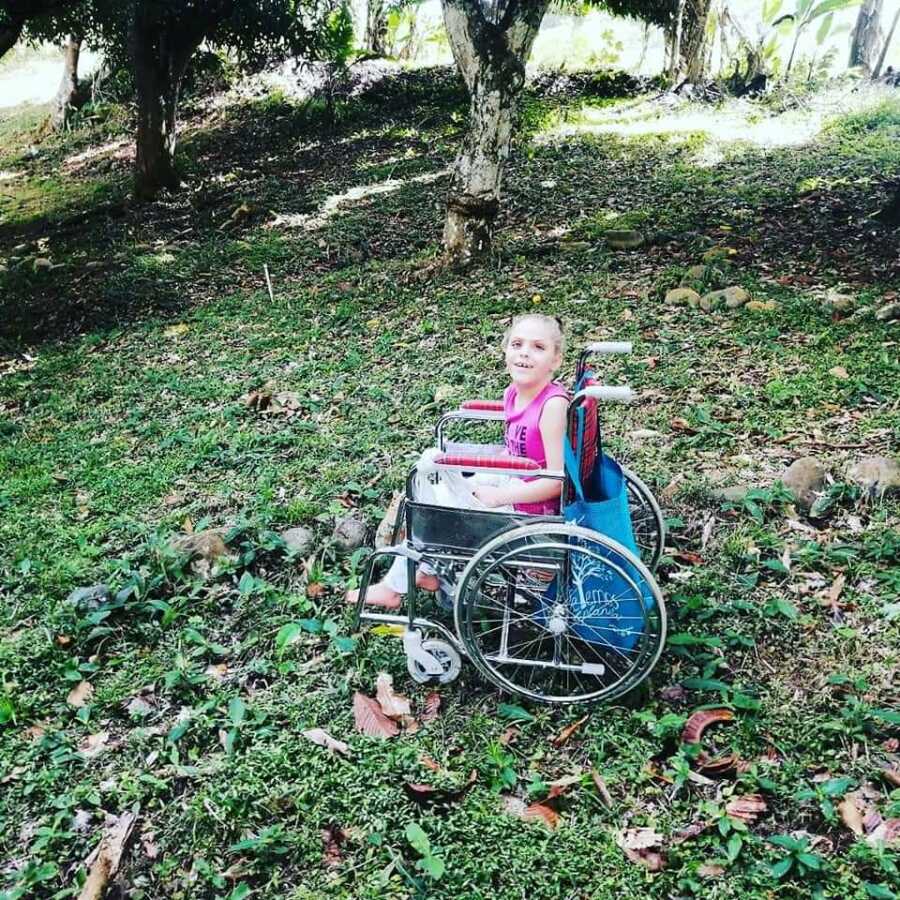 little girl in a wheel chair in the woods