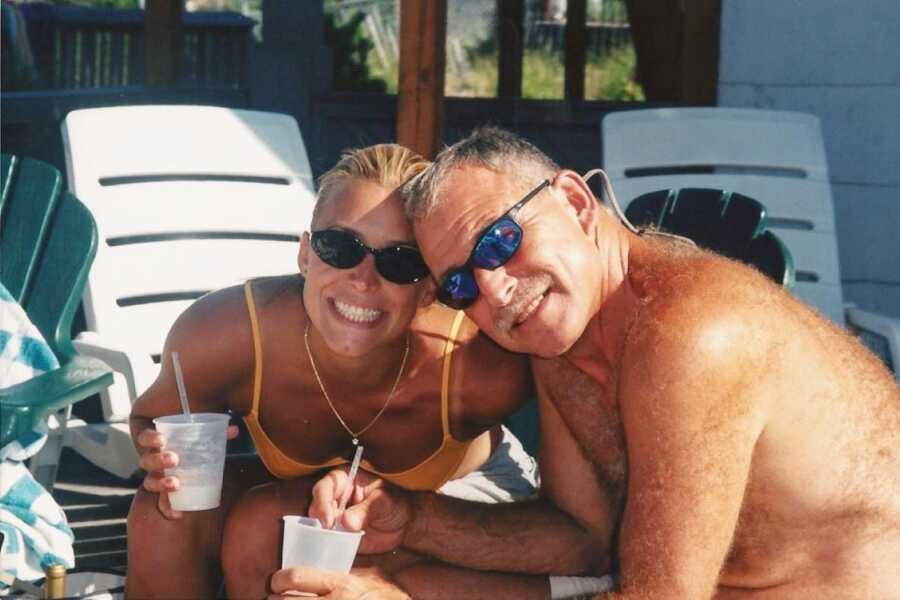 Father and daughter take a photo together while enjoying drinks by the poolside