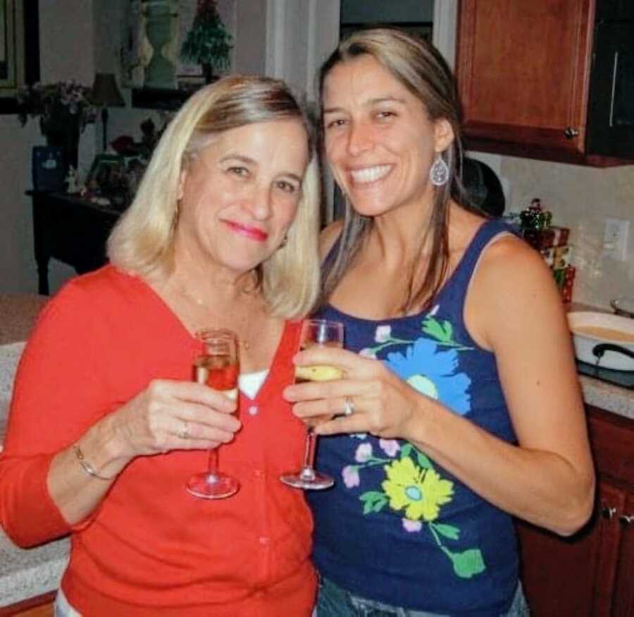 Mom and daughter smile for a photo in a kitchen while holding drinks