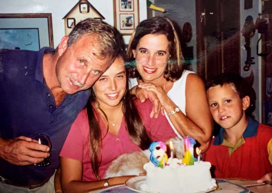 Young woman takes a photo with her parents with her 18th birthday cake in front of them