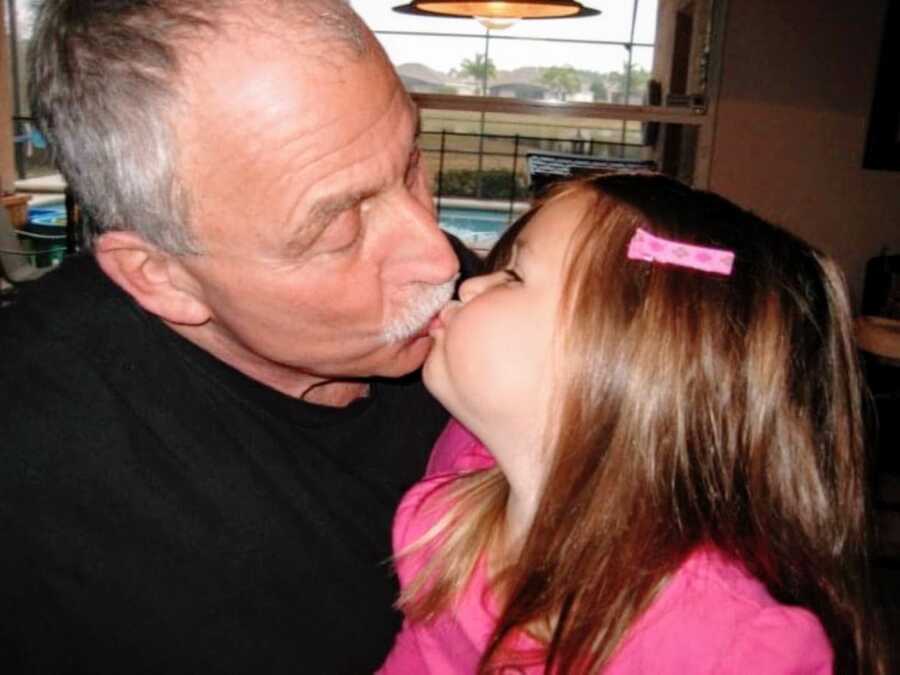 Grandpa kisses his granddaughter while spending some quality family time together