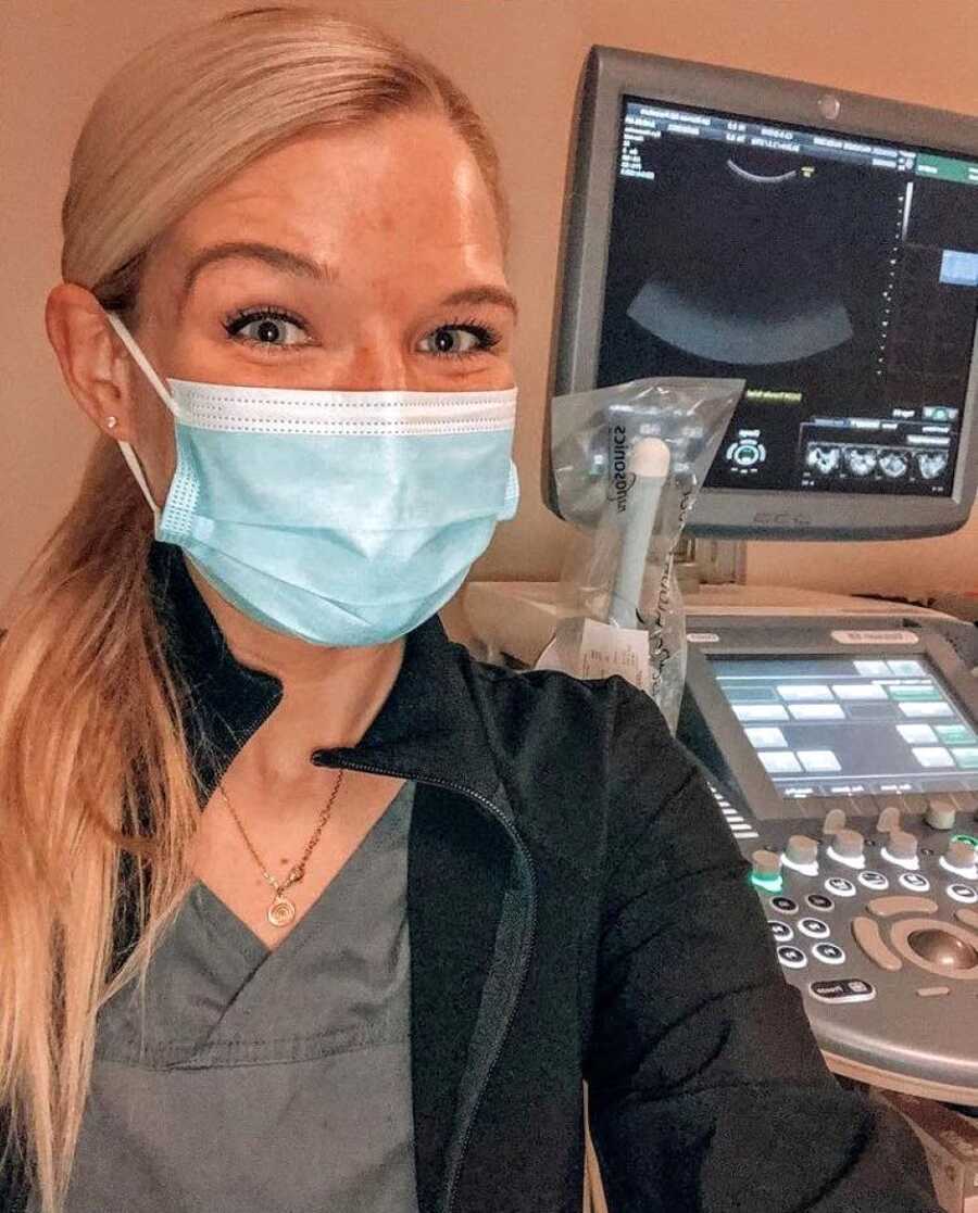 Woman battling infertility smiles under her facemask while taking a selfie at the doctor's