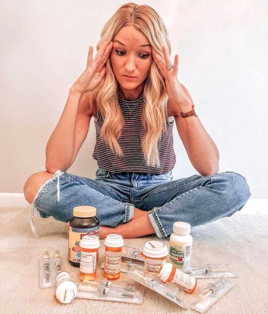 Woman experiencing infertility looks stressed while looking down at the medication she has to take to try and conceive