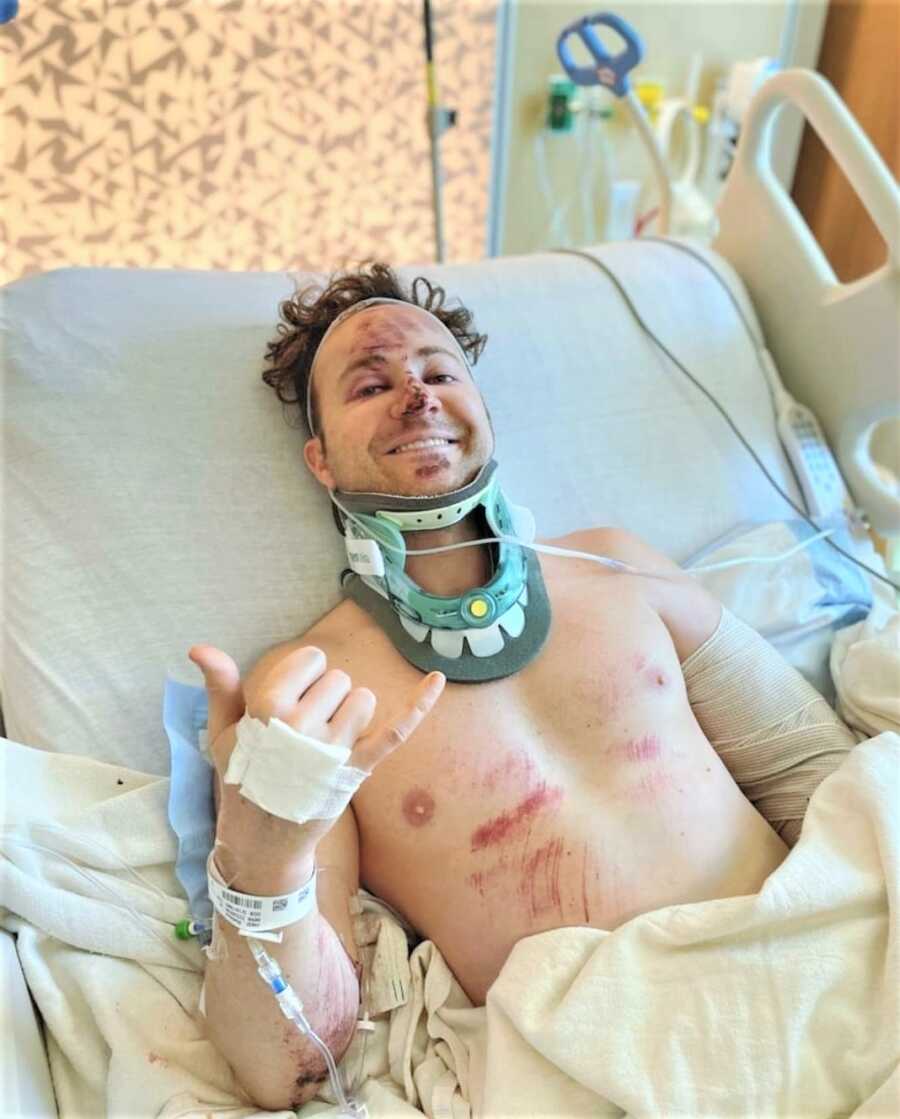 severely injured man laying on a hospital bed smiling 