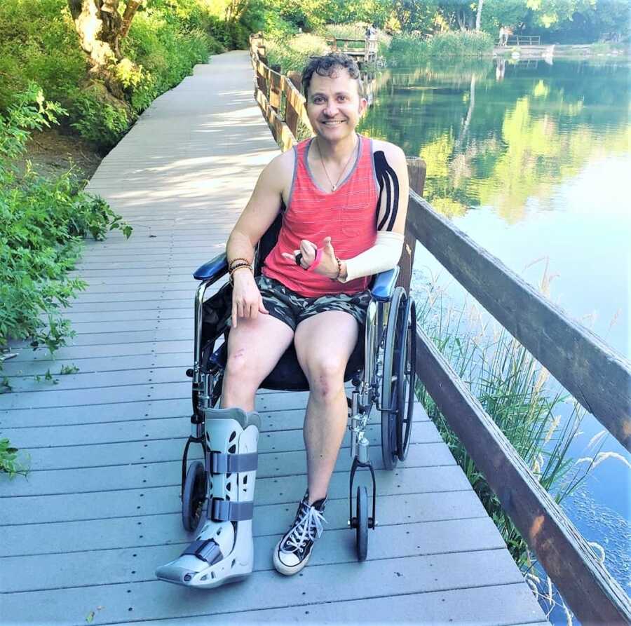 man sitting on a wheelchair smiling on a wood bridge 