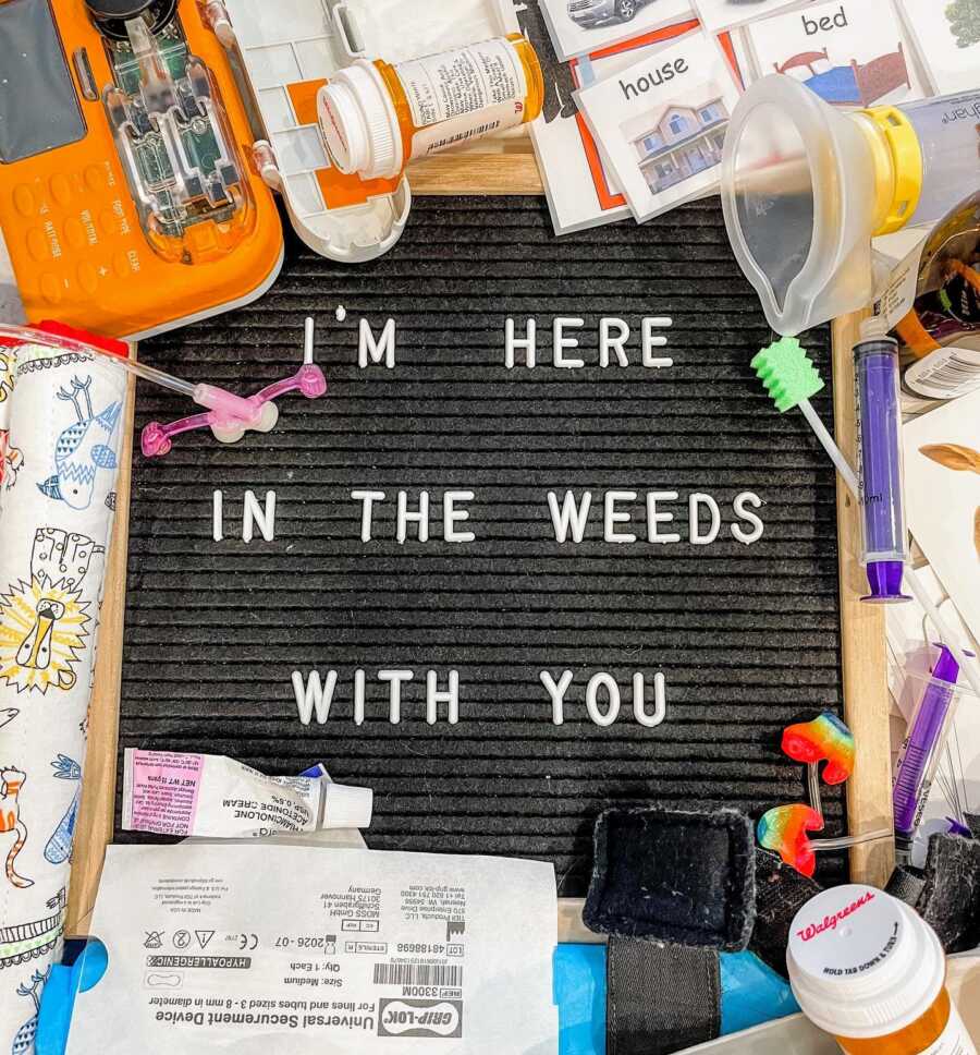 Special needs mom takes a photo of a letterboard with "I'm here in the weeds with you" with supplies for her child around it