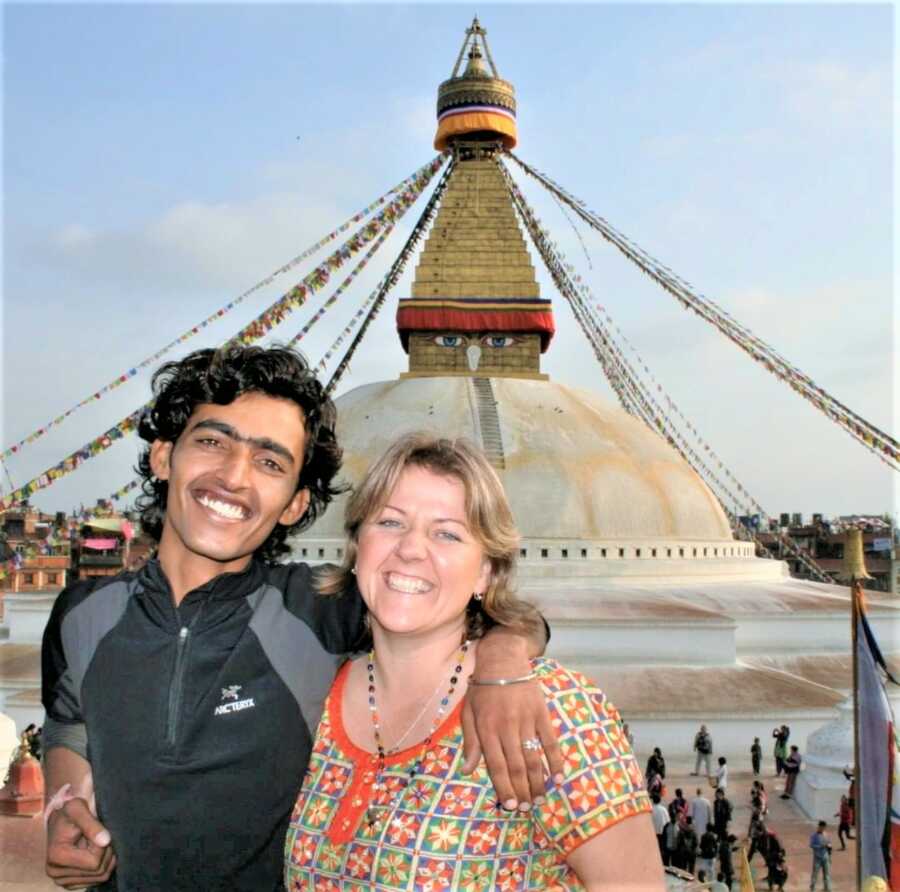 Interracial couple smiling while standing in front of a tower in Nepal’s historic center 