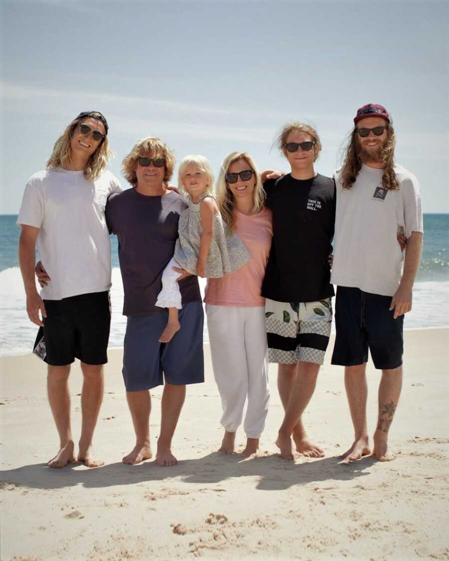 family with their newest addition taking a family photo on the beach