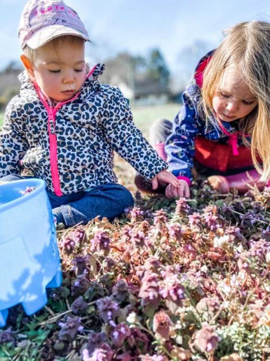 Sister pick lavender plants in their backyard while wearing colorful jackets