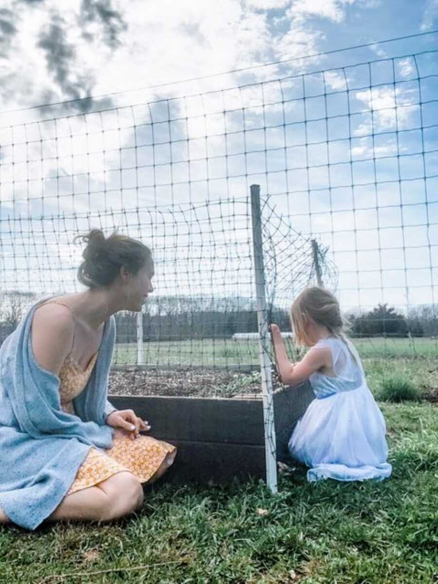 mom helps her daughter plant flowers in their garden
