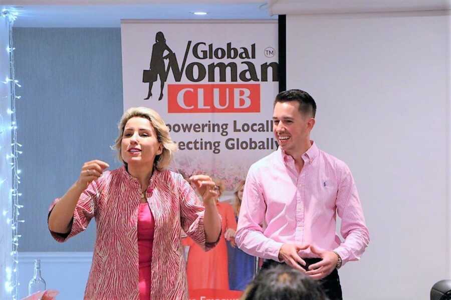 a young man and a woman giving a speech at the Global Woman Club