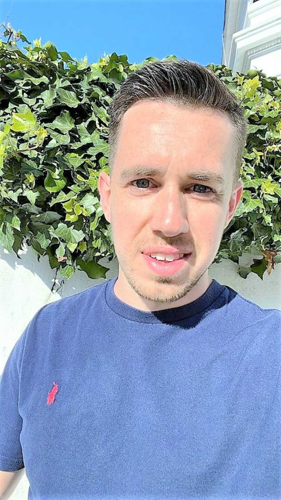 selfie of man wearing a navy t-shirt with the sunlight reflected on his face