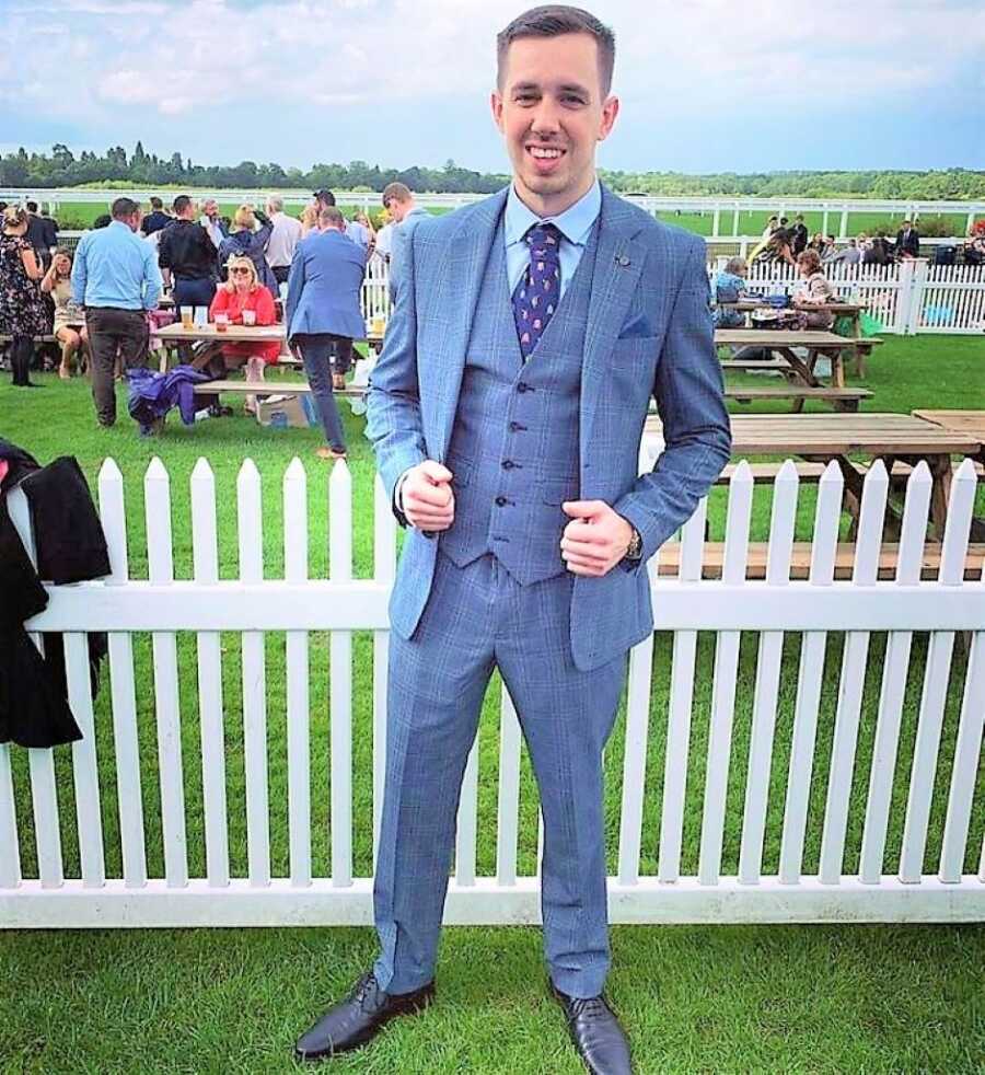 Young man wearing a navy suit at a public outdoor event 