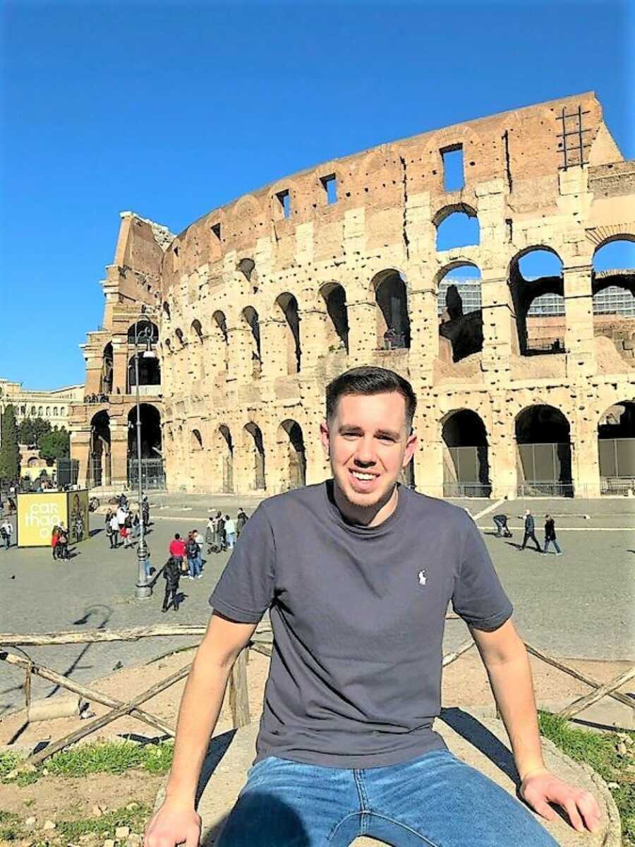 Young man smiling with the Roman Coliseum in the back 