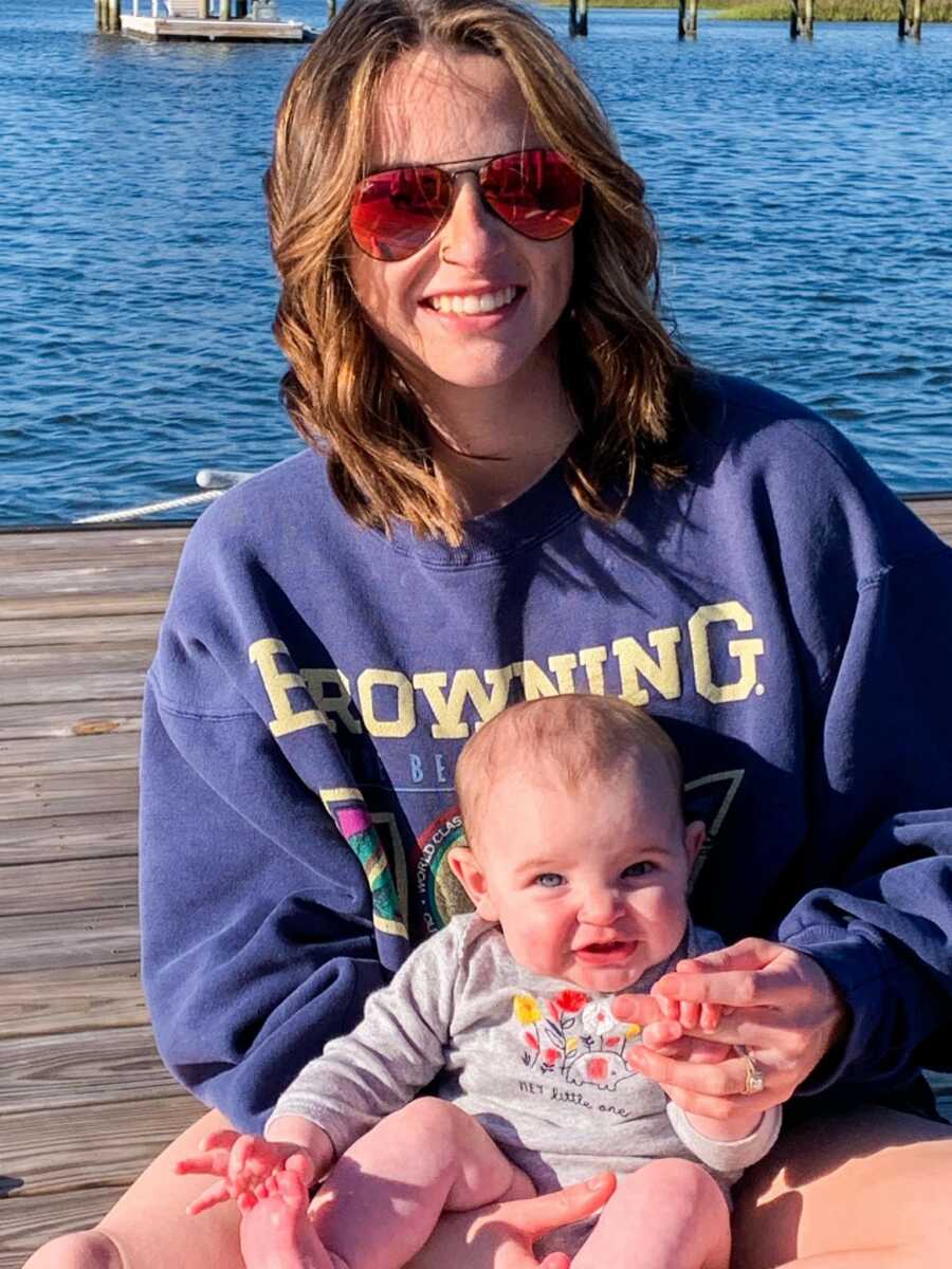 mom holding her daughter on a dock smiling