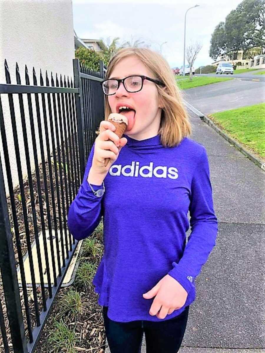 Special needs girl eats an ice cream cone in an Adidas hoodie
