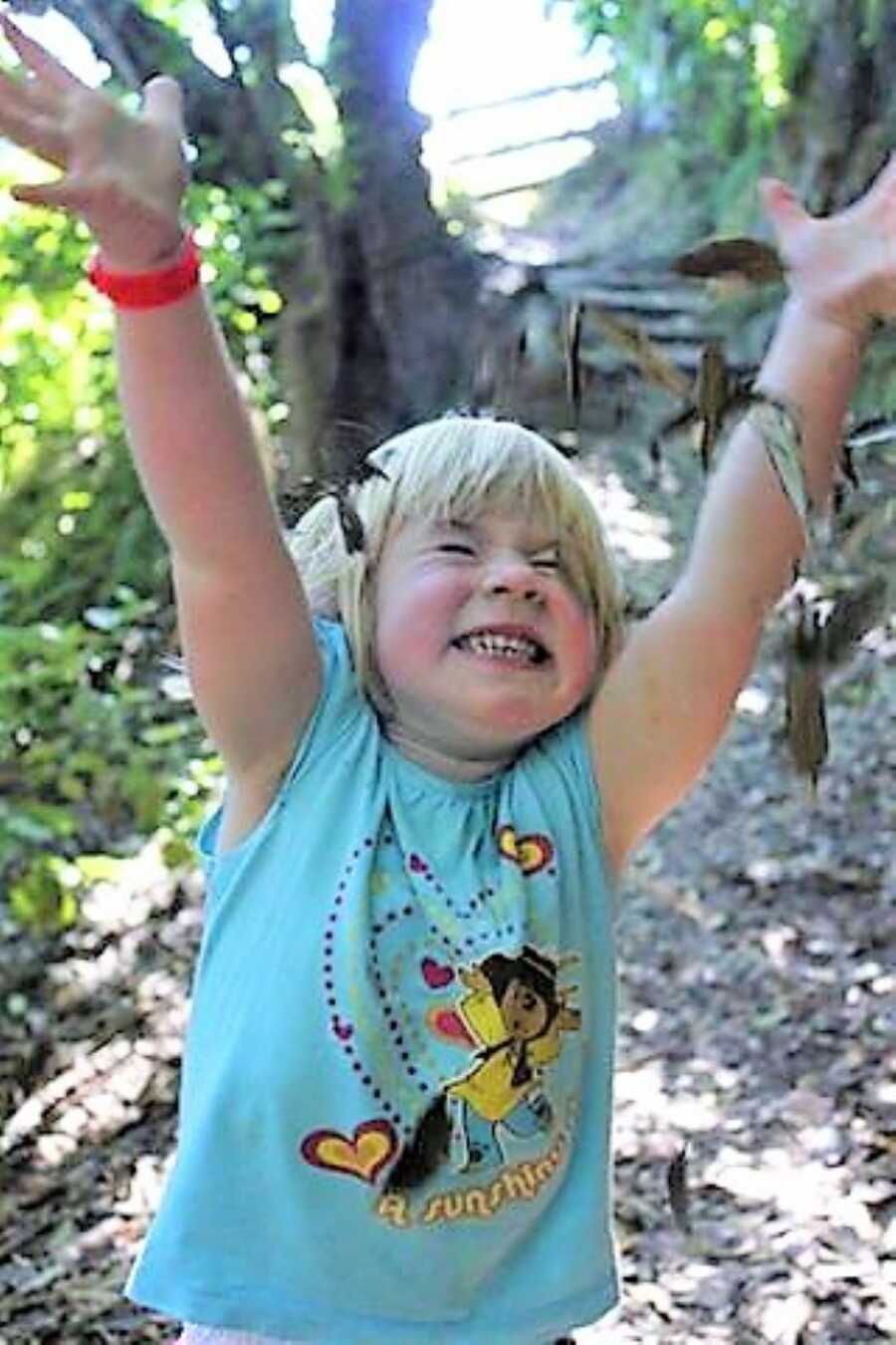 toddler girl throwing leaves up in the air while looking happy