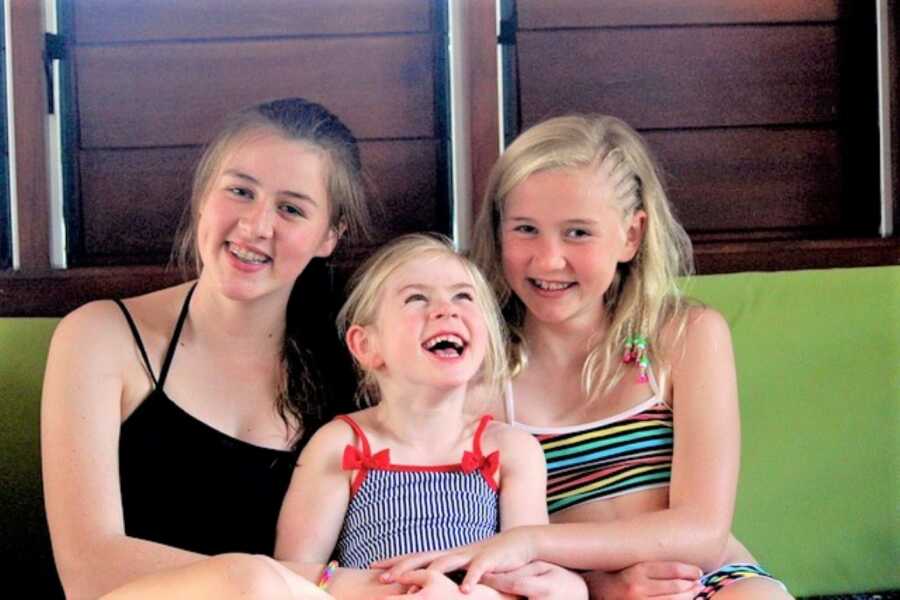 three sisters smiling and wearing bathing suits 