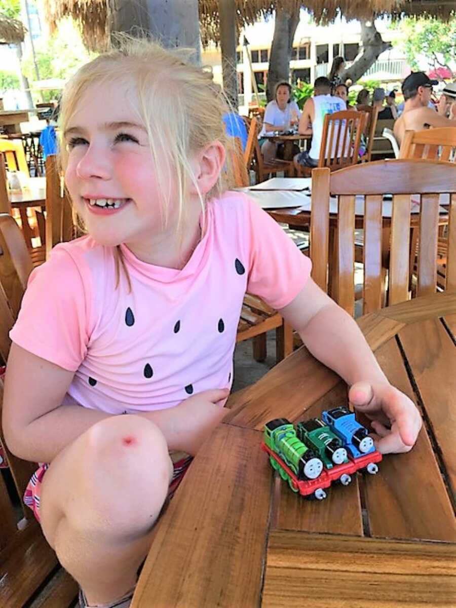 young blonde girl smiling and playing with toys at a restaurant 