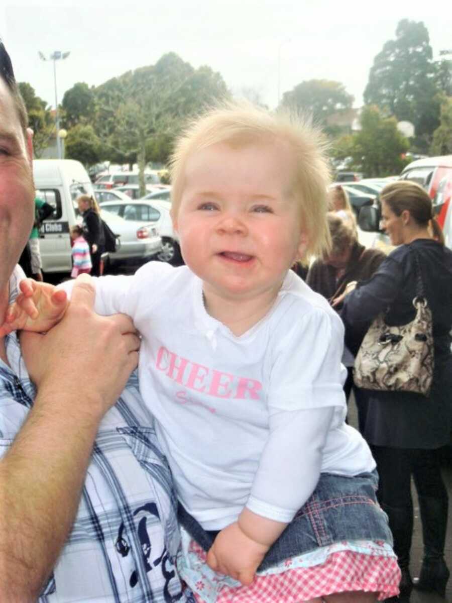 baby girl smiling while being carried by her dad