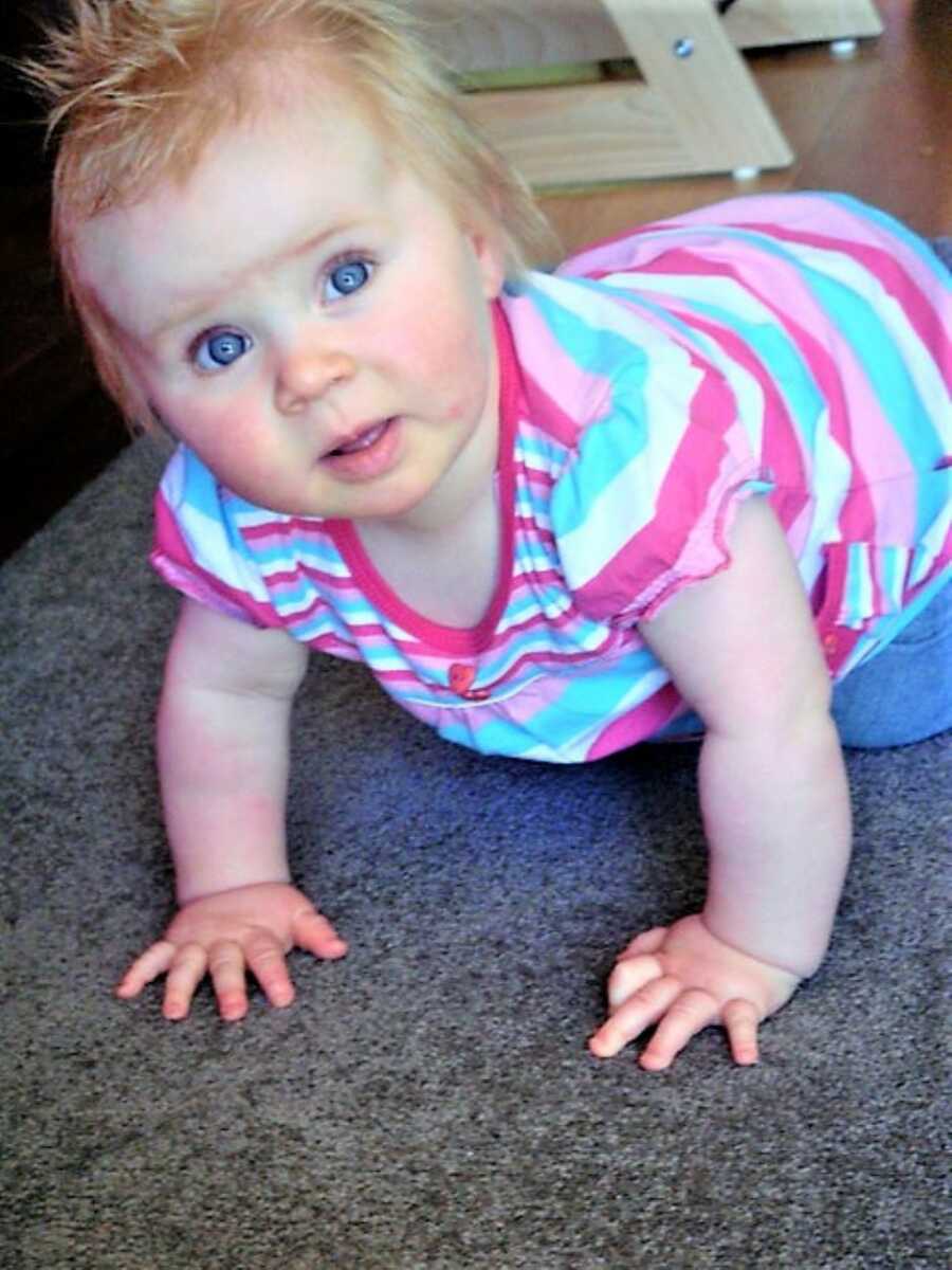 blue-eyed baby girl crawling on the carpeted floor