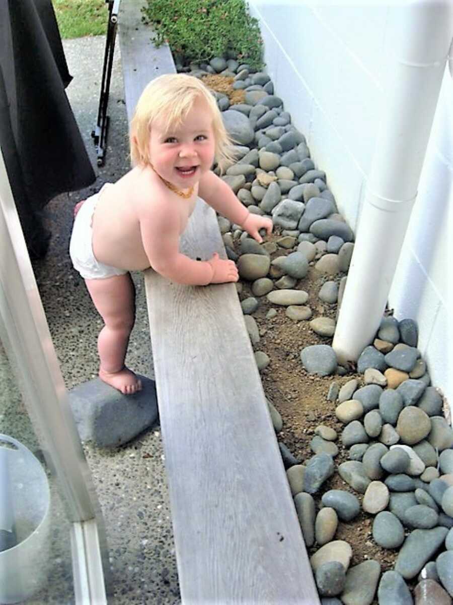 Toddler girl playing with rocks outside wearing pampers