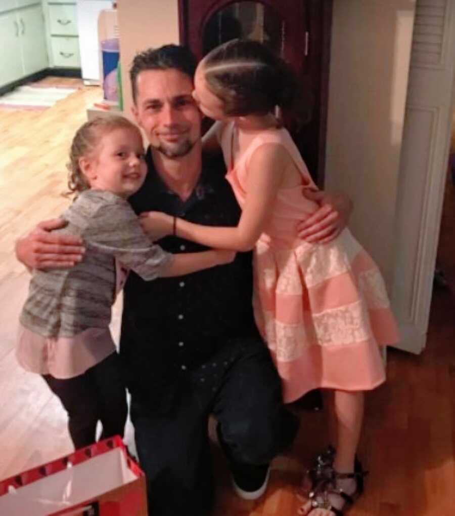 Two daughters hug and kiss their dad before going to a daddy daughter dance