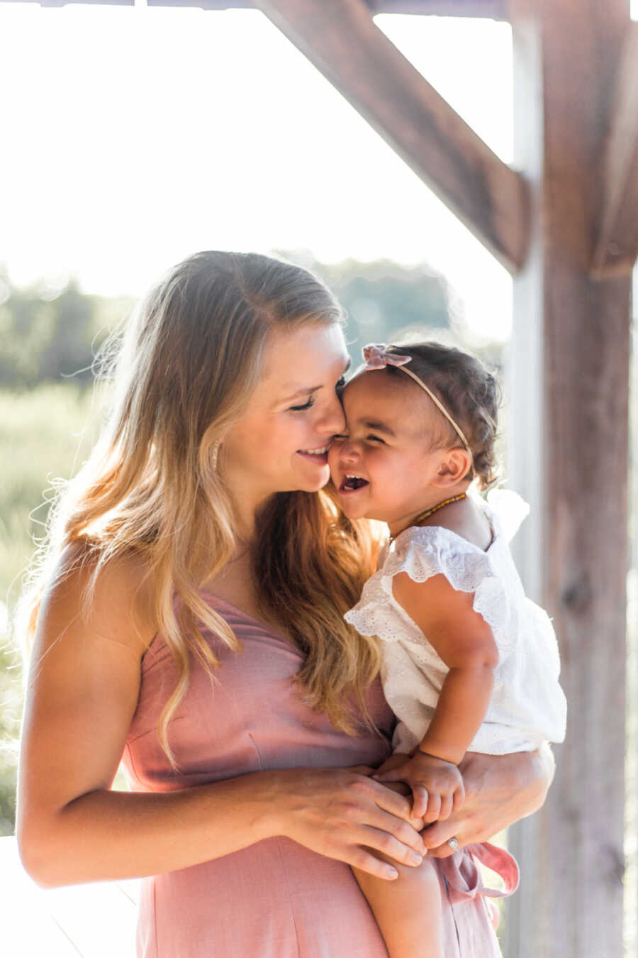 Mom holding her toddler daughter in her arms while the girl laughs