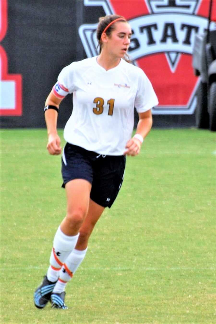 Young woman playing soccer in a black and white uniform 