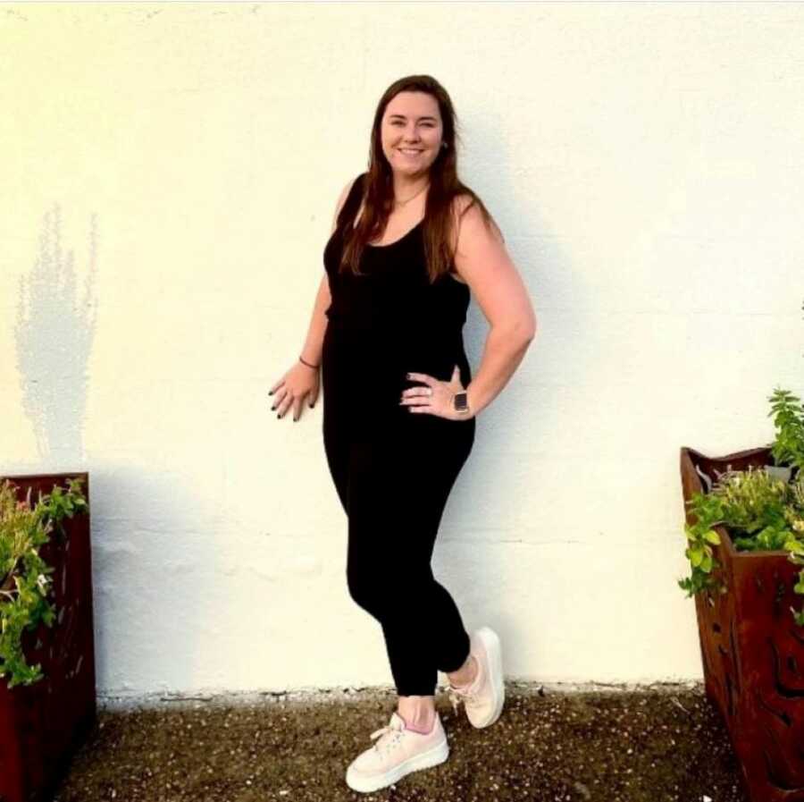 young woman in sportwear standing in front of a wall 