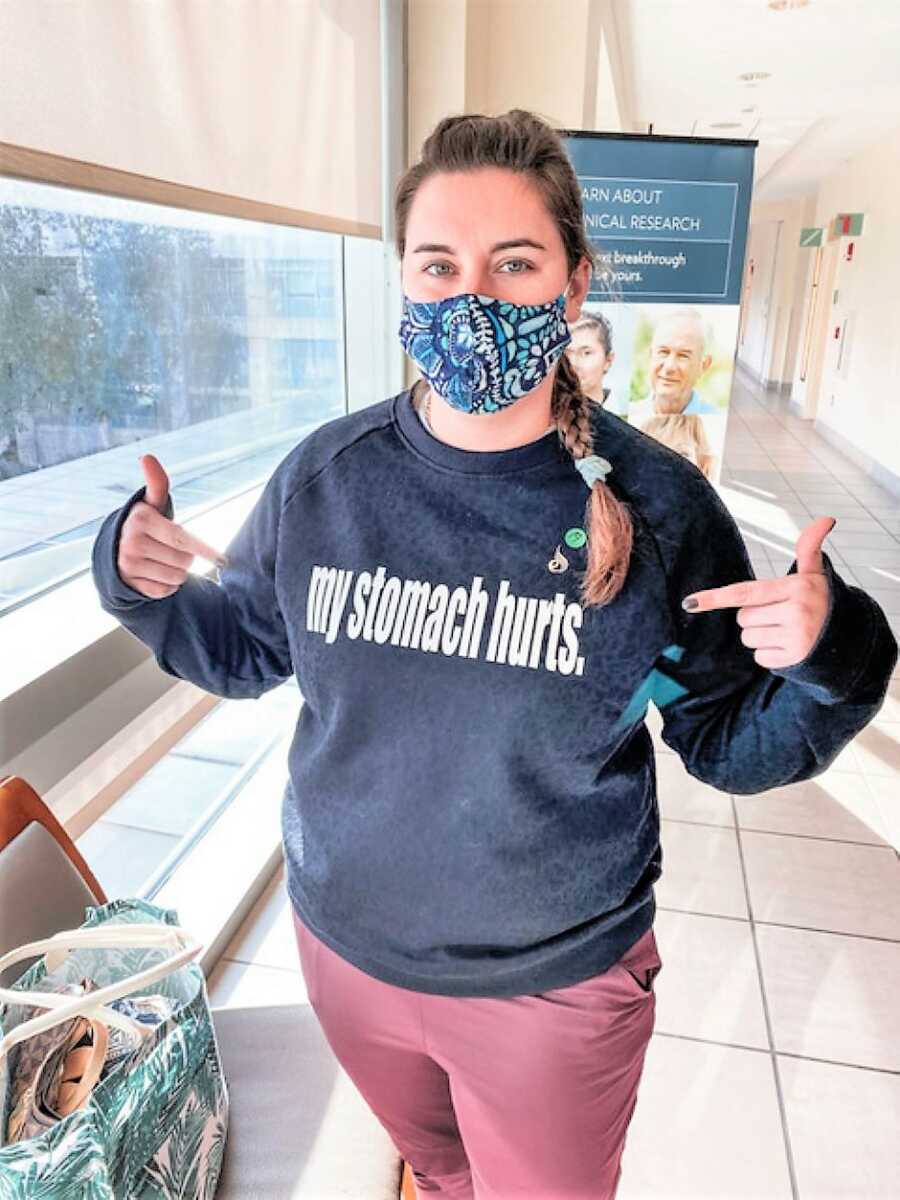 young woman wearing a sweatshirt that says "my stomach hurts"