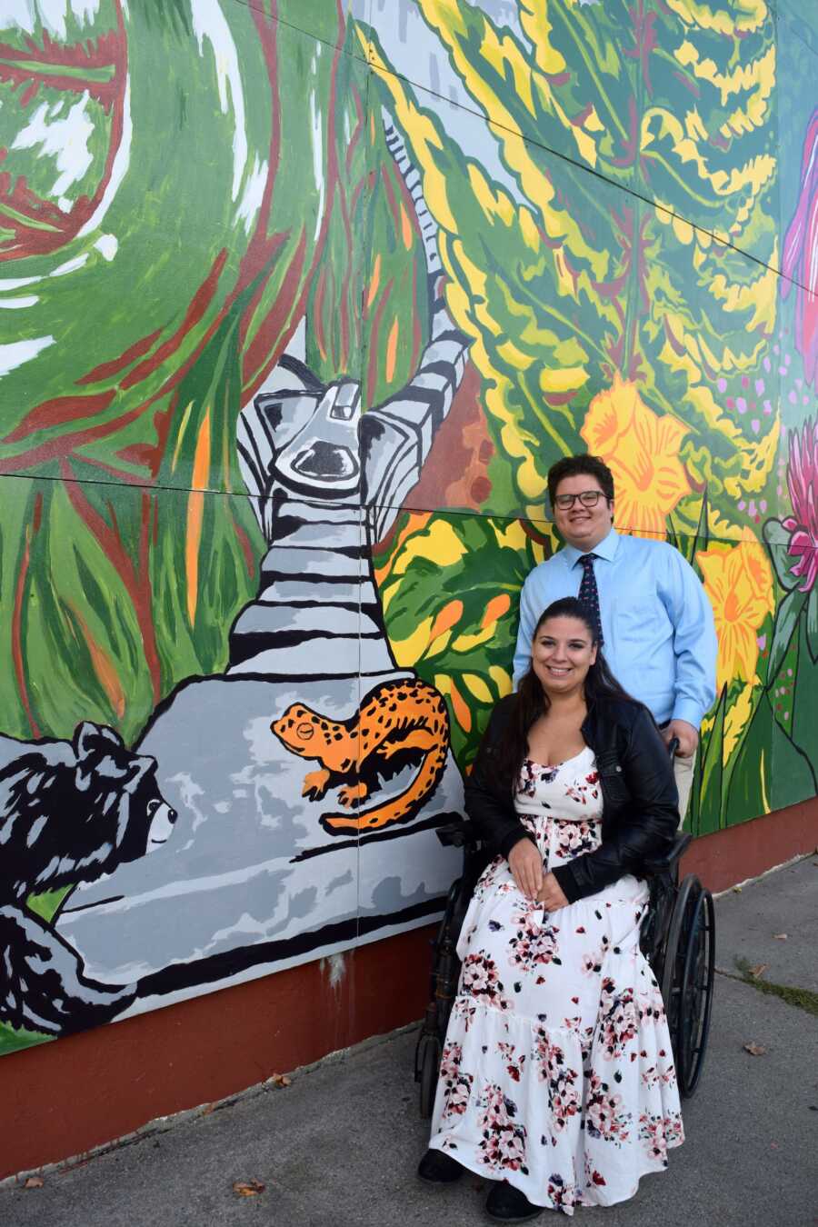 woman with her friend posing by a mural