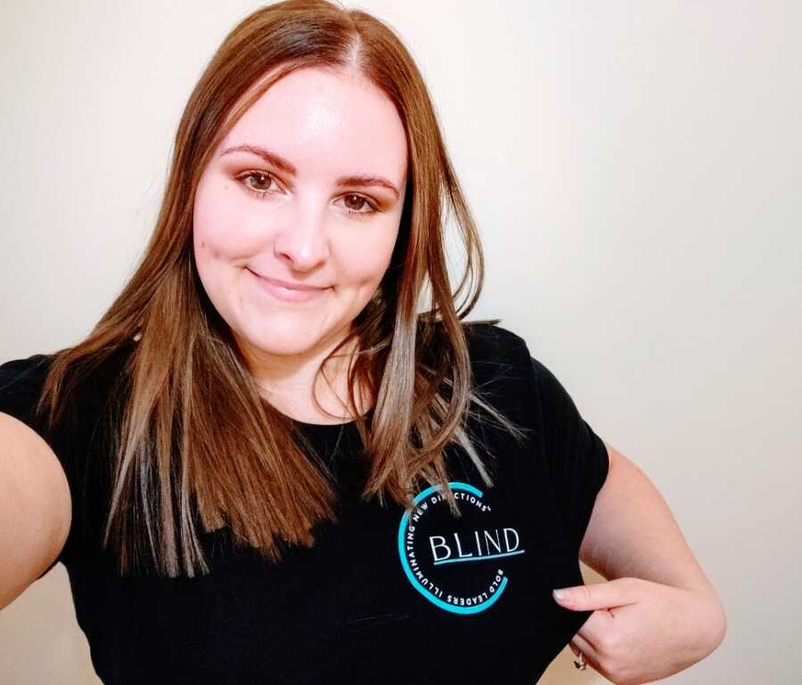 A visually impaired woman with long brown hair wearing a black T-shirt