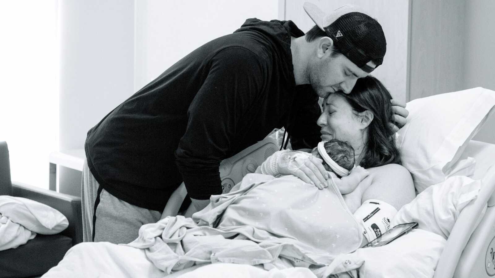 A husband and wife lean over the body of their stillborn daughter