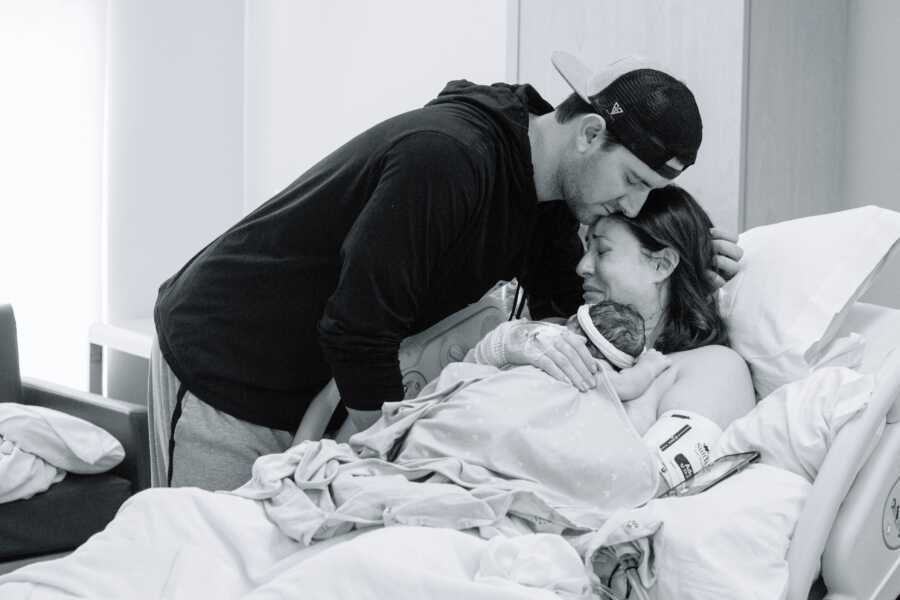 A husband and wife lean over the body of their stillborn daughter