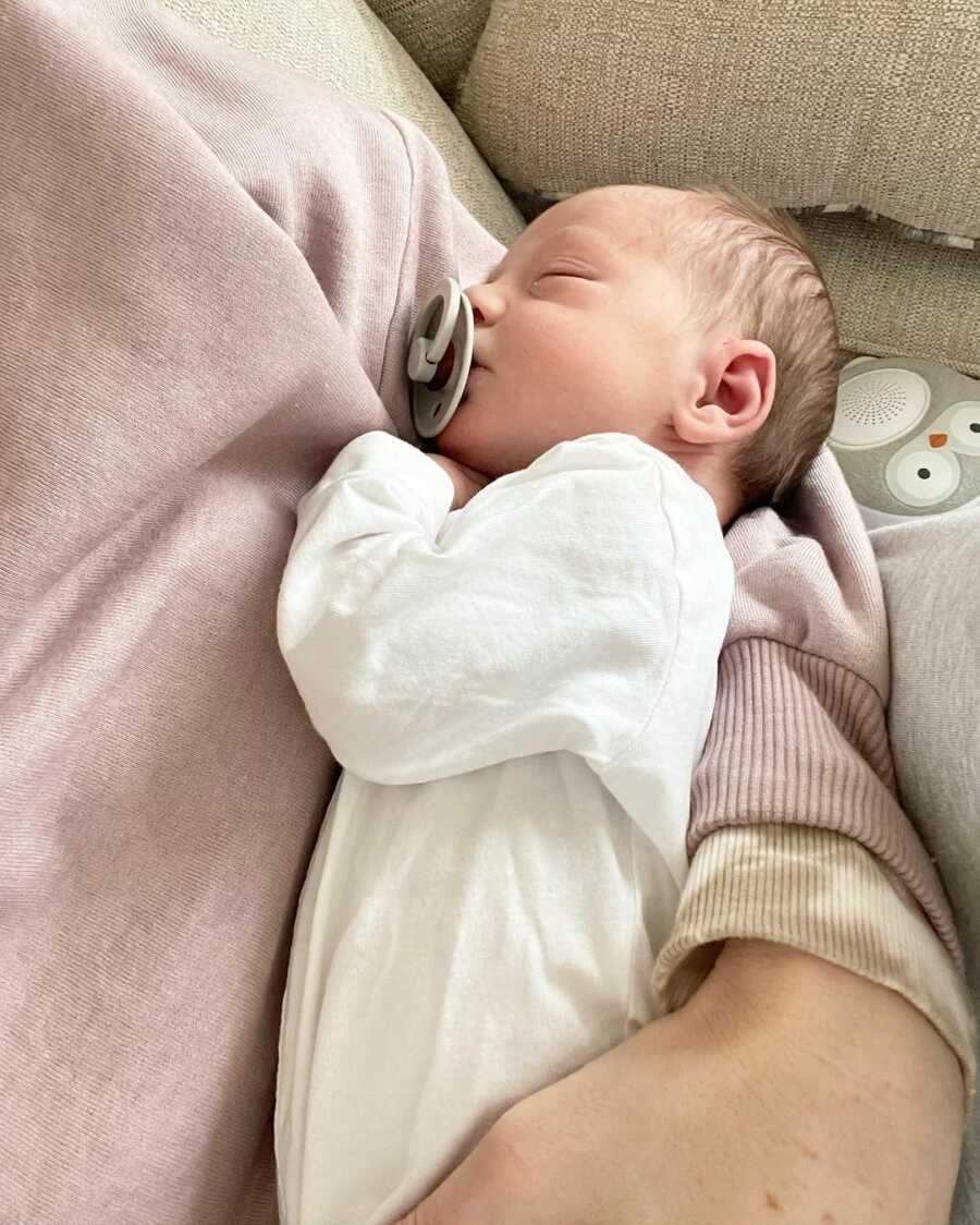 mother holds her newborn baby while they are sleeping