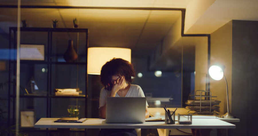 Shot of a young businesswoman looking stressed while using a laptop during a late night at work