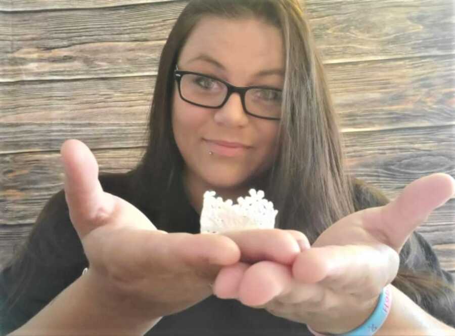 Woman holds tiny crochet crown for babies born prematurely.