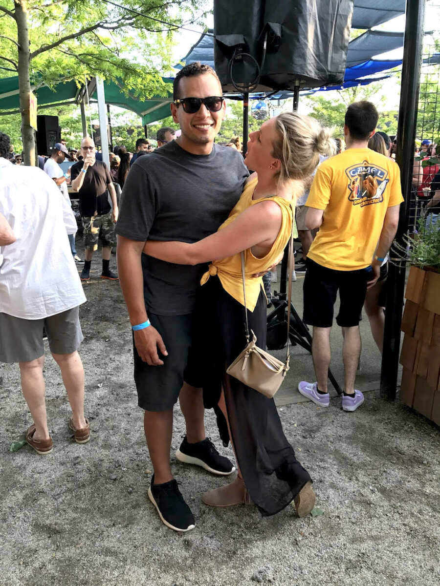 Woman wearing yellow tank top wraps her arms around man in grey shirt and shorts.